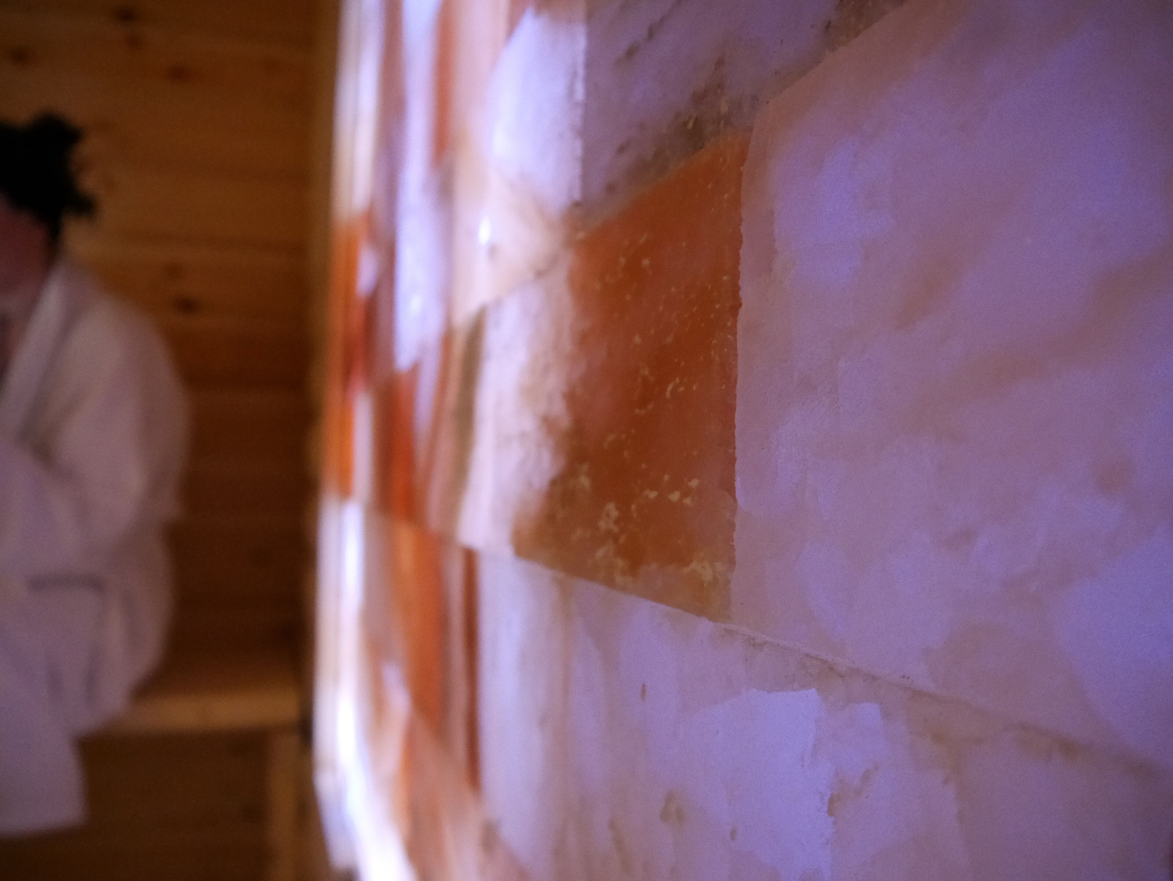 A close-up of a wall with peeling paint and a wooden panel.