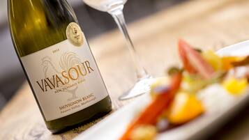 Una botella de vino blanco Sauvignon Blanc Vavasour y una copa de vino sobre una mesa con un plato de comida.