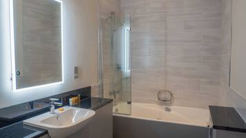 A modern bathroom with a sink, mirror, and bathtub.
