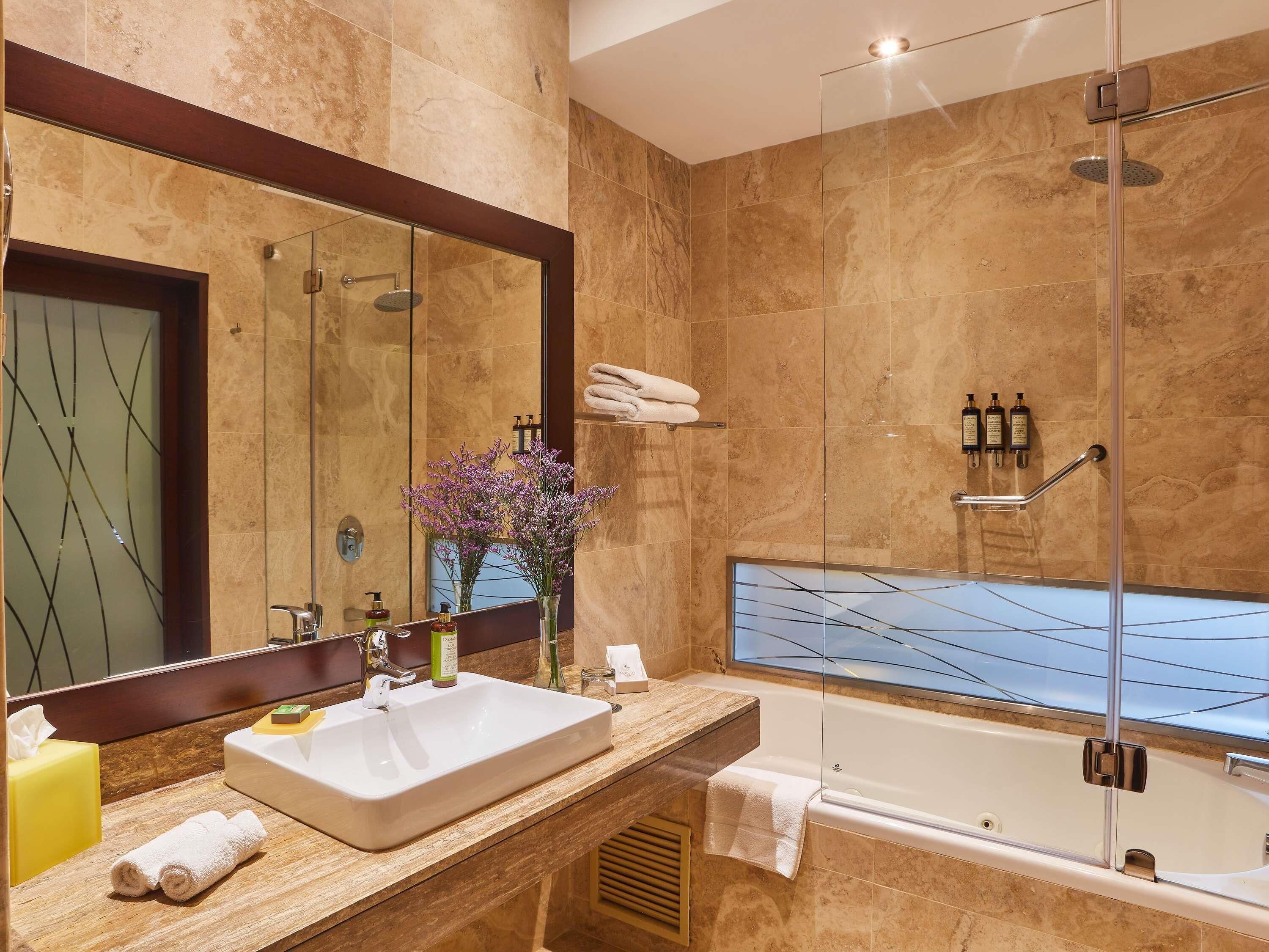 A modern bathroom with a large mirror, a sink, a shower, and a bathtub.