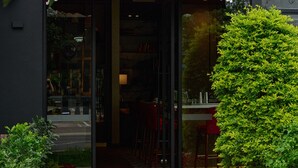 A restaurant entrance with a red awning, glass doors, and a stone pathway leading to the entrance. - Manto Hotel Lima - MGallery  Collection (Lima)