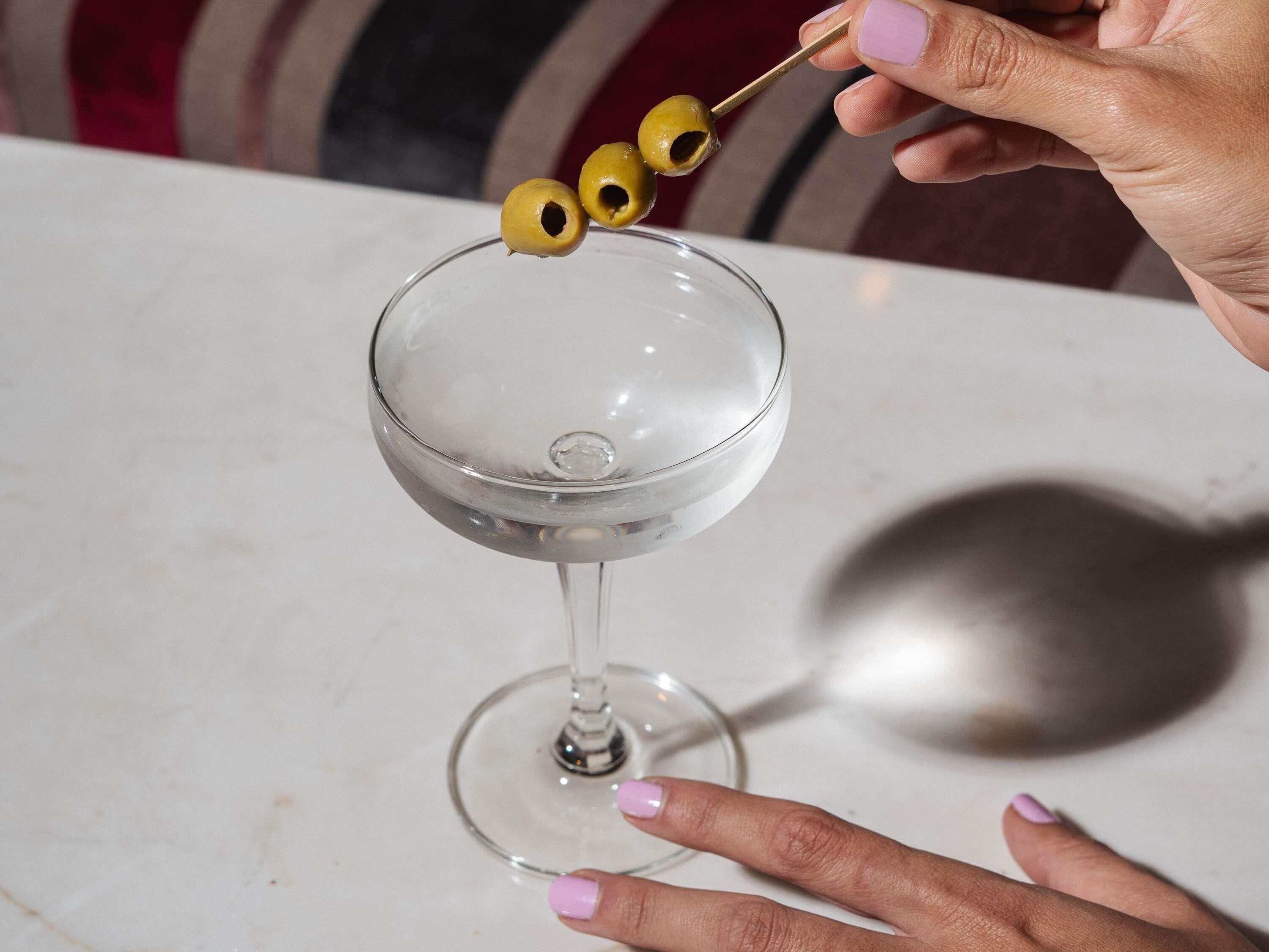 A clear glass martini glass on a marble surface.