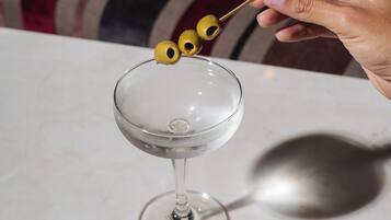 A hand holding a cocktail shaker with olives.