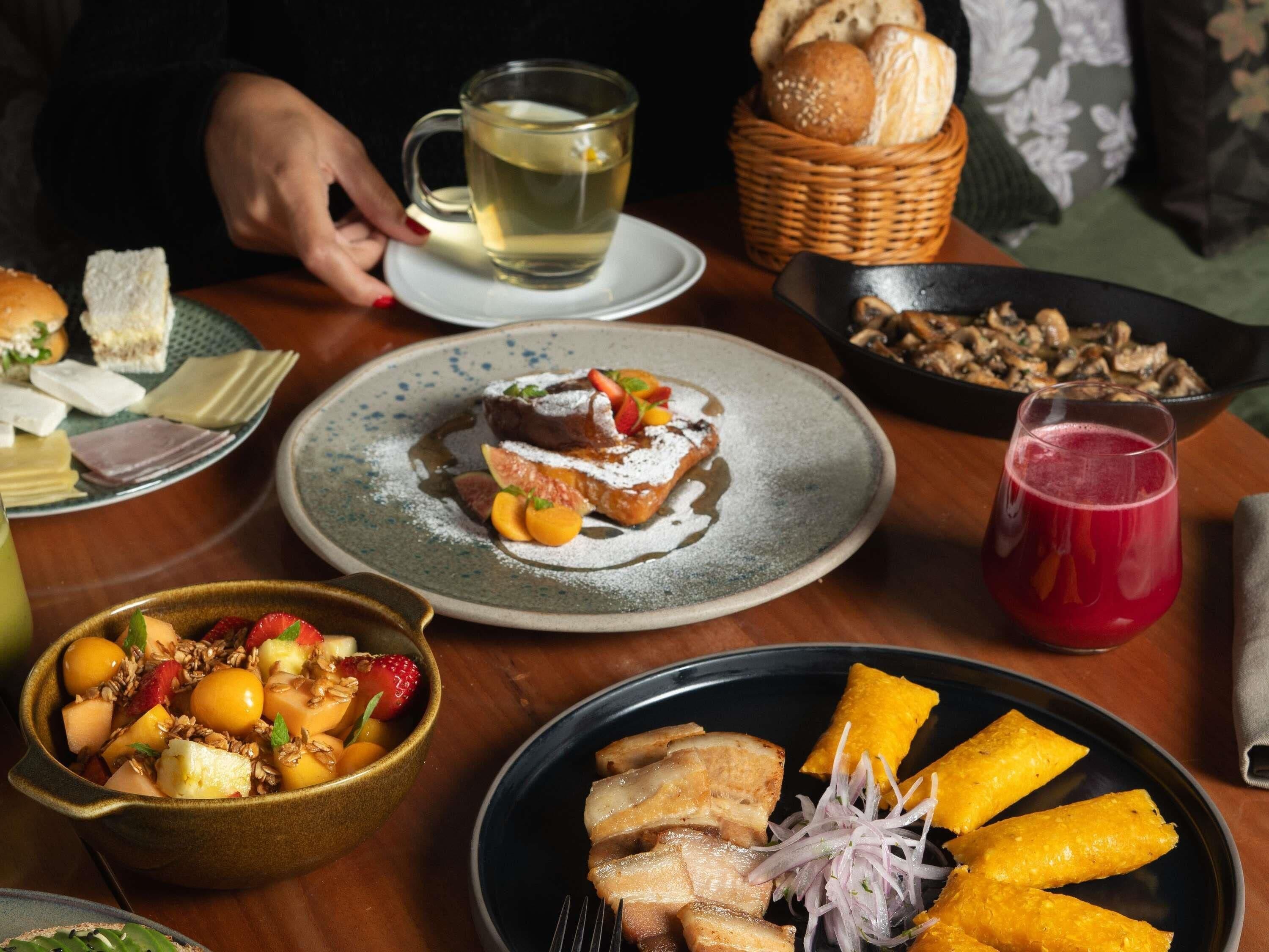 A dining table with various dishes, a cup of tea, and a basket of bread.