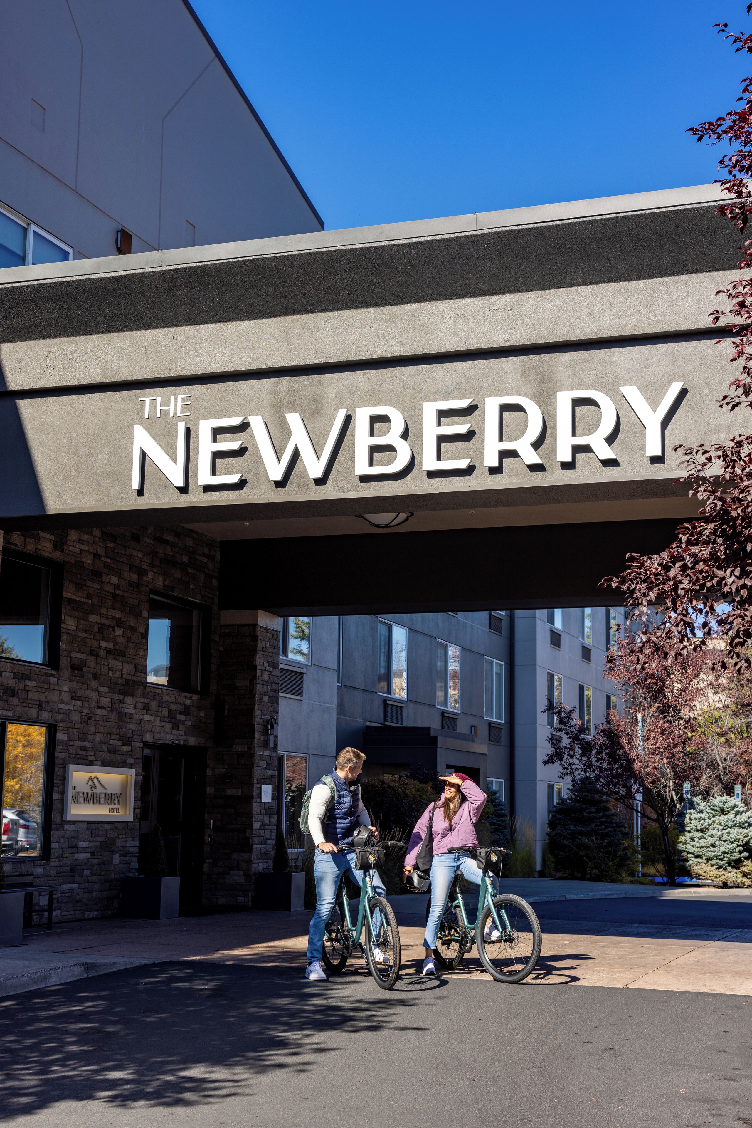 A building with a sign reading "The Newberry" and two people on bicycles in front.