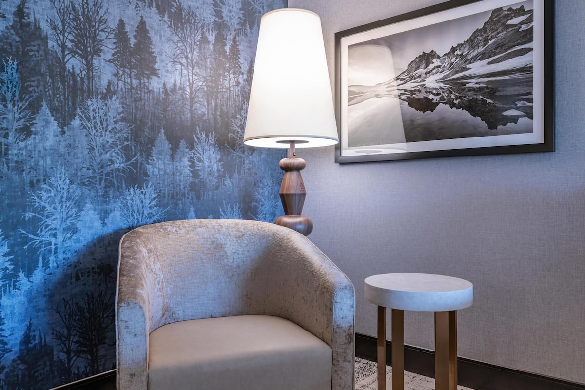 Quarto com parede texturizada, luminária, cadeira e quadro emoldurado.