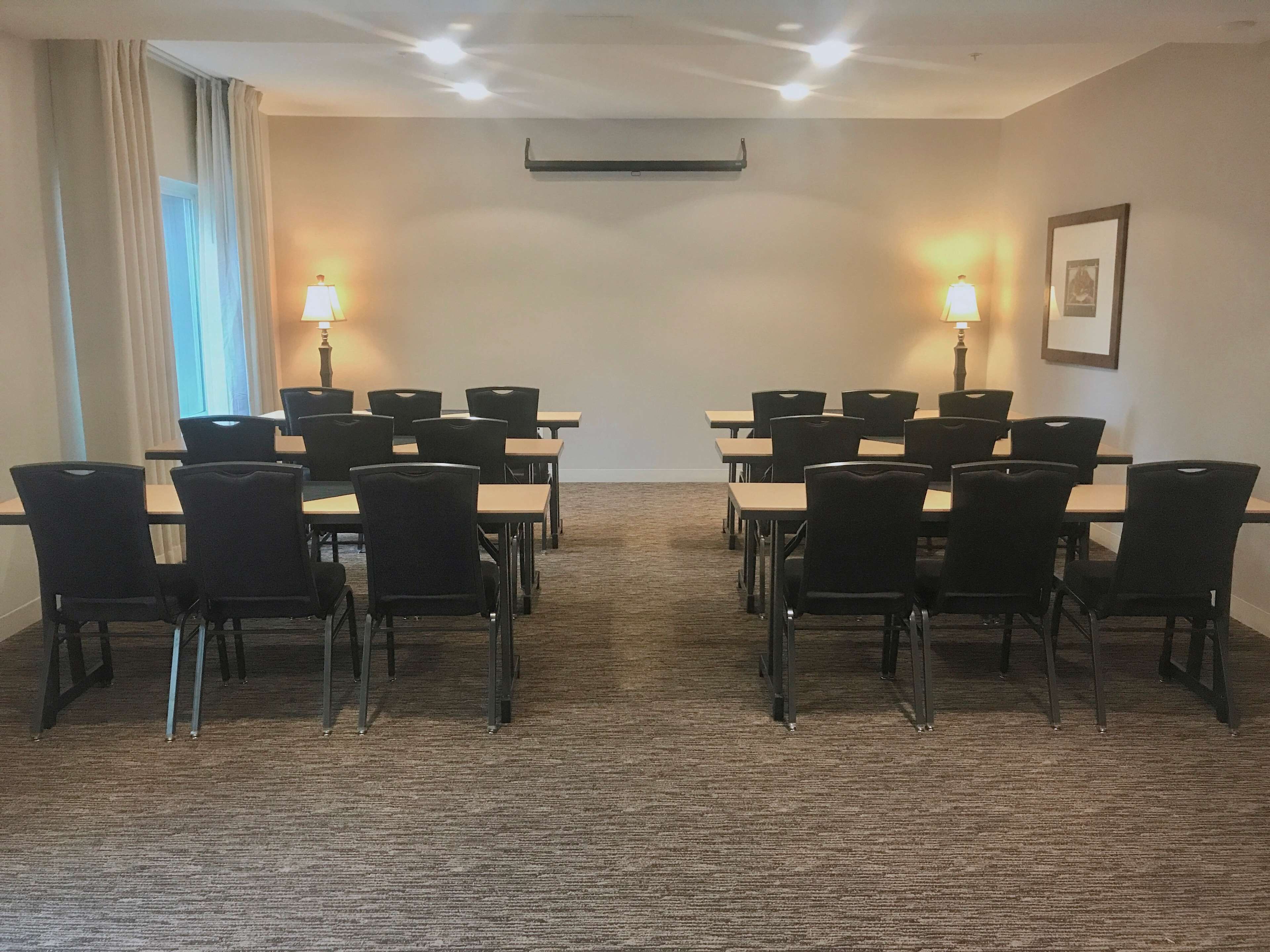 A conference room with a carpeted floor, tables, and chairs arranged for meetings.