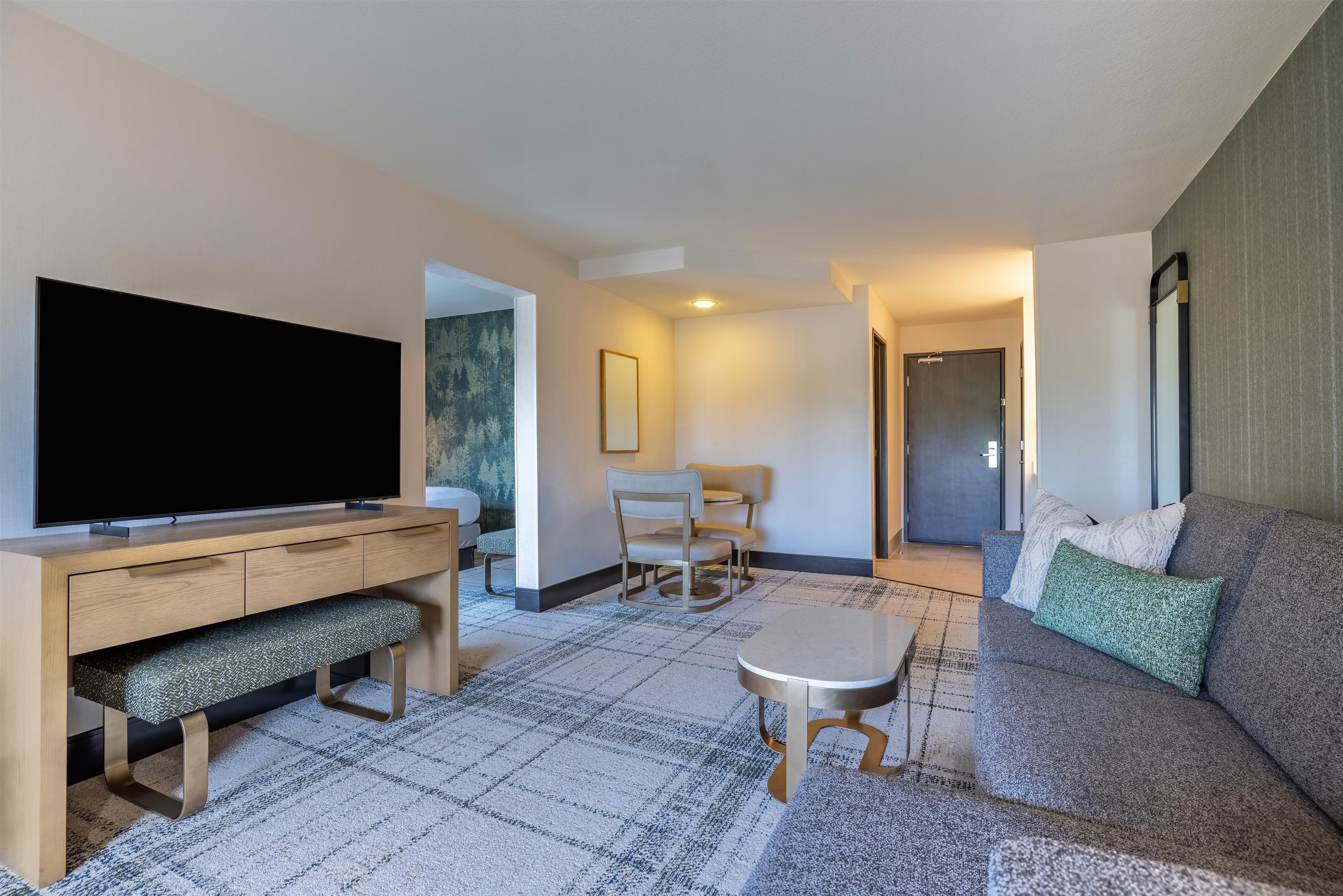 A modern living room with a flat-screen TV, a sofa, a coffee table, and a dining area.