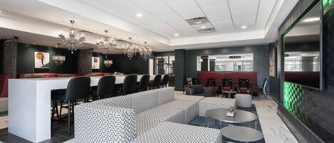 A modern hotel lobby with a dining area, seating arrangements, and a bar.