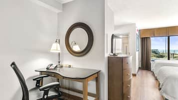 A hotel room with a desk, chair, dresser, and a bed.