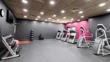 Un gimnasio con cintas de correr, elípticas y bancos de pesas.