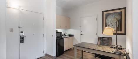 Een kleine keuken met een magnetron, spoelbak en kastjes.