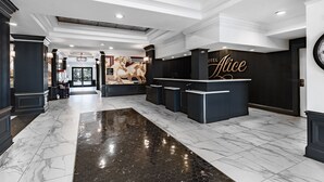 A hotel lobby with a reception desk, marble flooring, and a large wall mural.