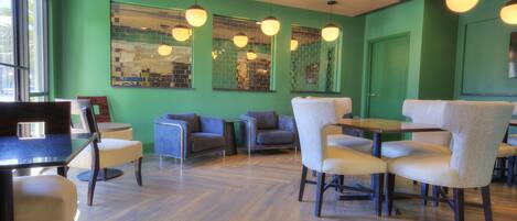 Un intérieur moderne avec des murs verts, un plancher en bois et différents types de mobilier, notamment des tables et des chaises.