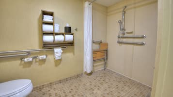 A bathroom with a toilet, a shelf with towels, a shower with grab bars, and a shower curtain.