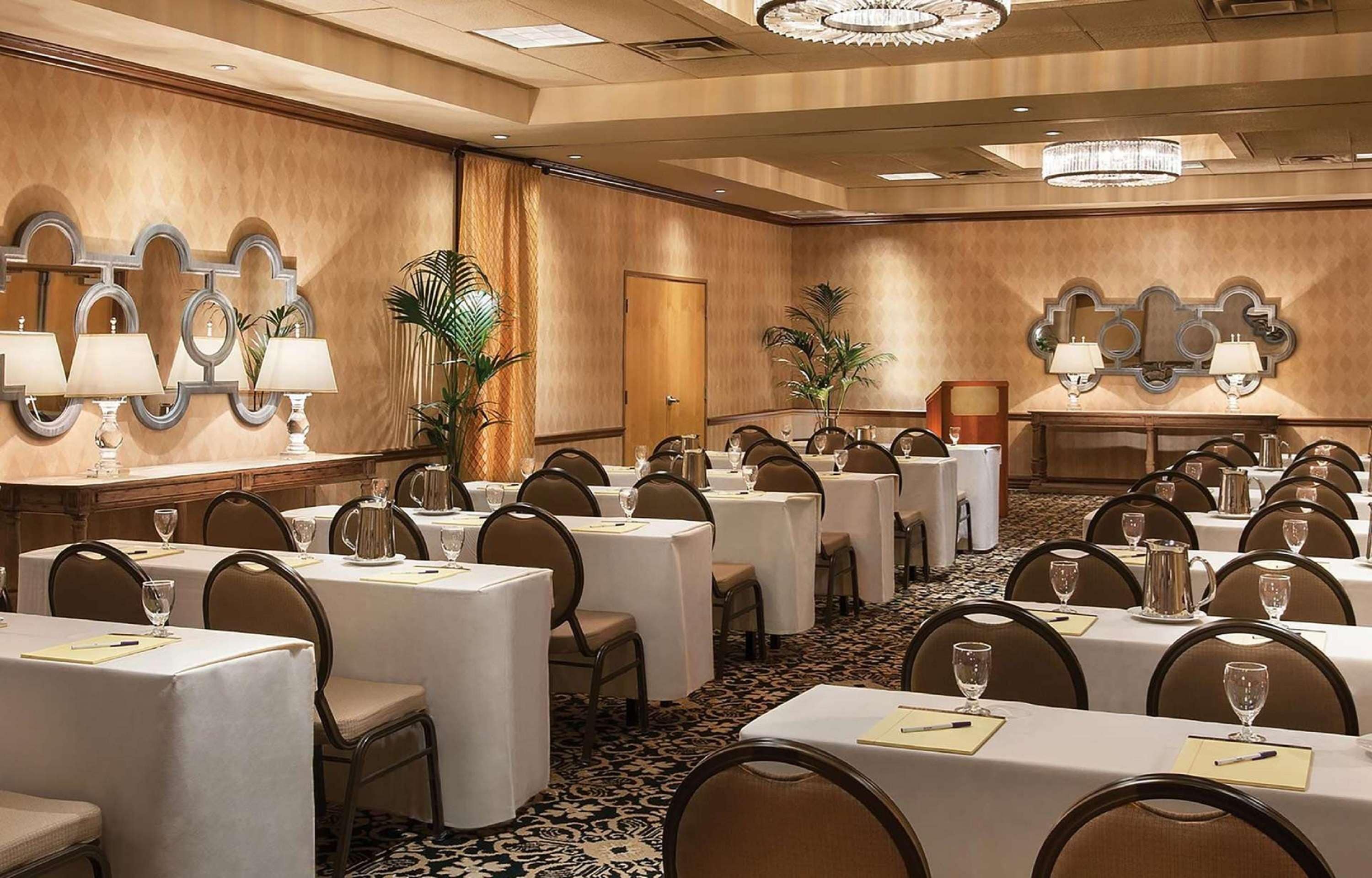 A conference room with round tables, chairs, and a chandelier.