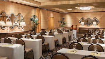 A conference room with round tables, chairs, and a chandelier.