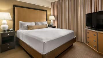 Ein Hotelzimmer mit einem großen Bett, zwei Nachttischen mit Lampen, einem Fernseher und einem Holzschrank.