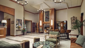 A spacious lobby with a fireplace, seating area, and a dining setup. - Sonesta Suites Scottsdale Gainey Ranch (Scottsdale)