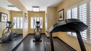 Une salle de sport équipée d’un tapis de course, d’un vélo elliptique et d’un vélo d’appartement.