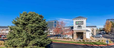 A Holiday Inn Express hotel with a prominent sign, surrounded by trees and parked cars.