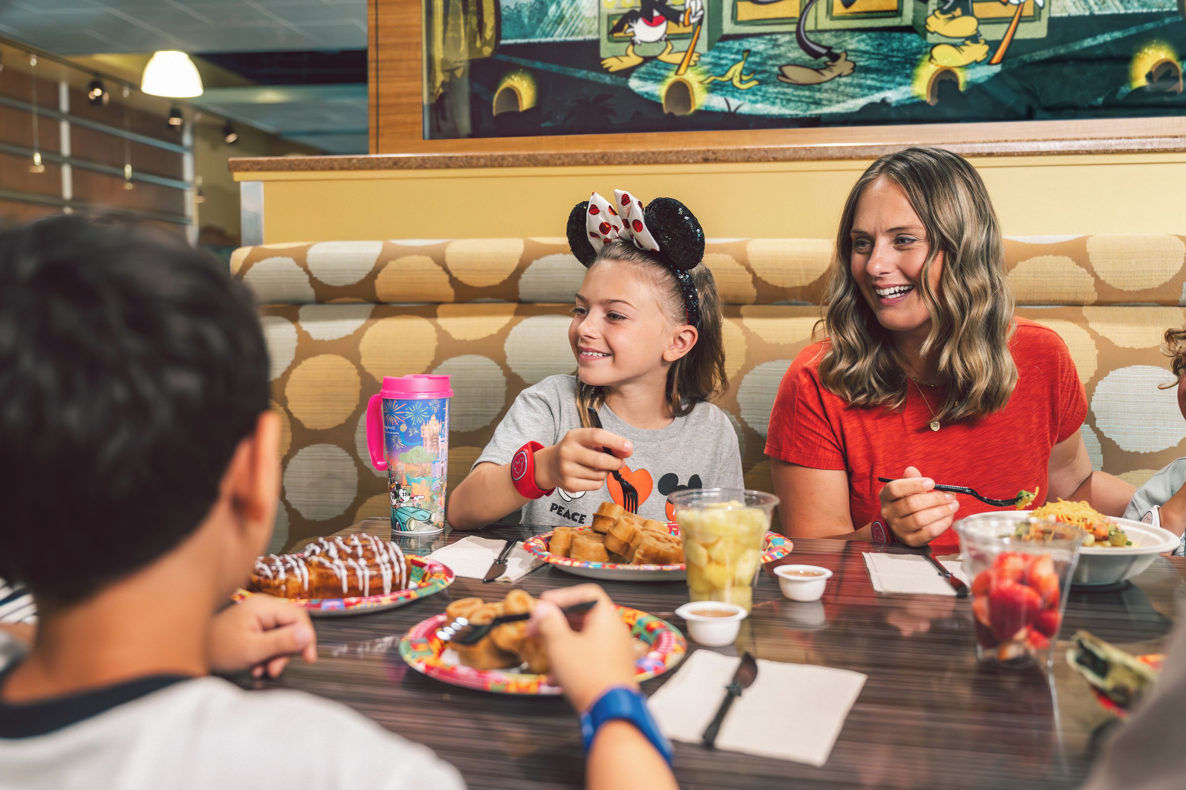 A family dining at a restaurant with a Mickey Mouse themed decor.
