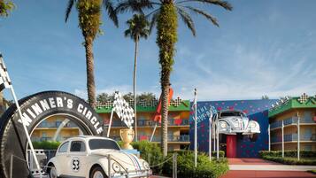 A vintage car parked in front of a building with a large tire arch labeled "WINNER'S CIRCLE".
