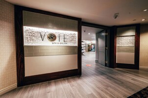 Zona de recepción con un cartel anunciando un spa y salón de belleza, suelo de madera y un diseño de interiores moderno.
