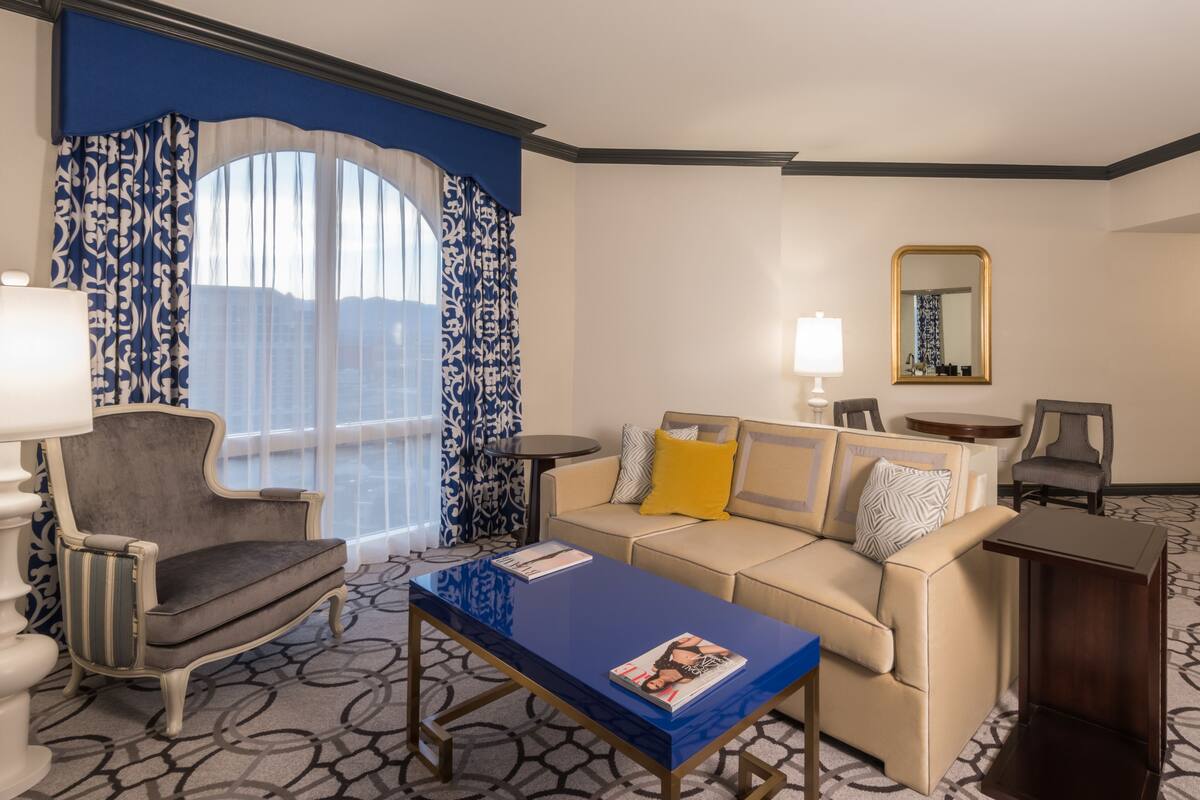 Una habitación de hotel moderna con sofá, sillón y una mesita de centro.