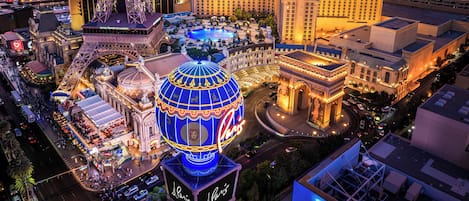 Una gran estructura en forma de cúpula iluminada con la palabra 'Paris' escrita en ella, rodeada de una zona bien iluminada con edificios y una piscina.