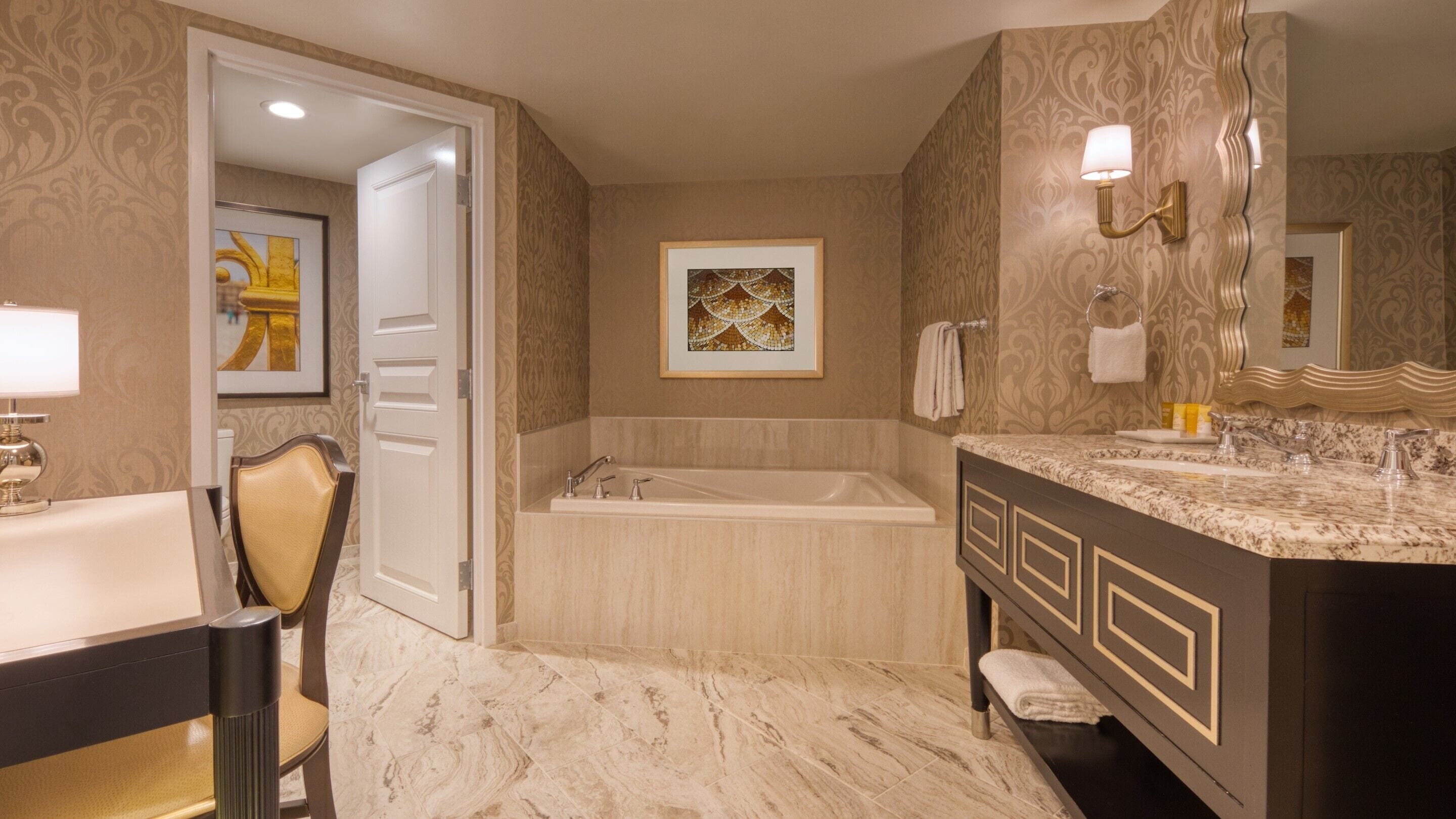 Un baño con una bañera, tocador con lavabo, espejo y una silla.