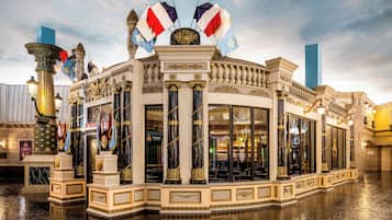 A grand building with ornate columns and flags, featuring large windows and a reflective floor.