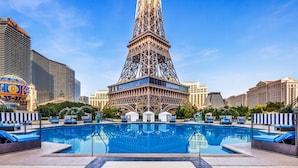 Un hôtel avec une piscine à l’avant, une grande tour en arrière-plan et un casino à proximité.