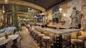 Un espace bar avec un long comptoir, des tabourets et une statue.