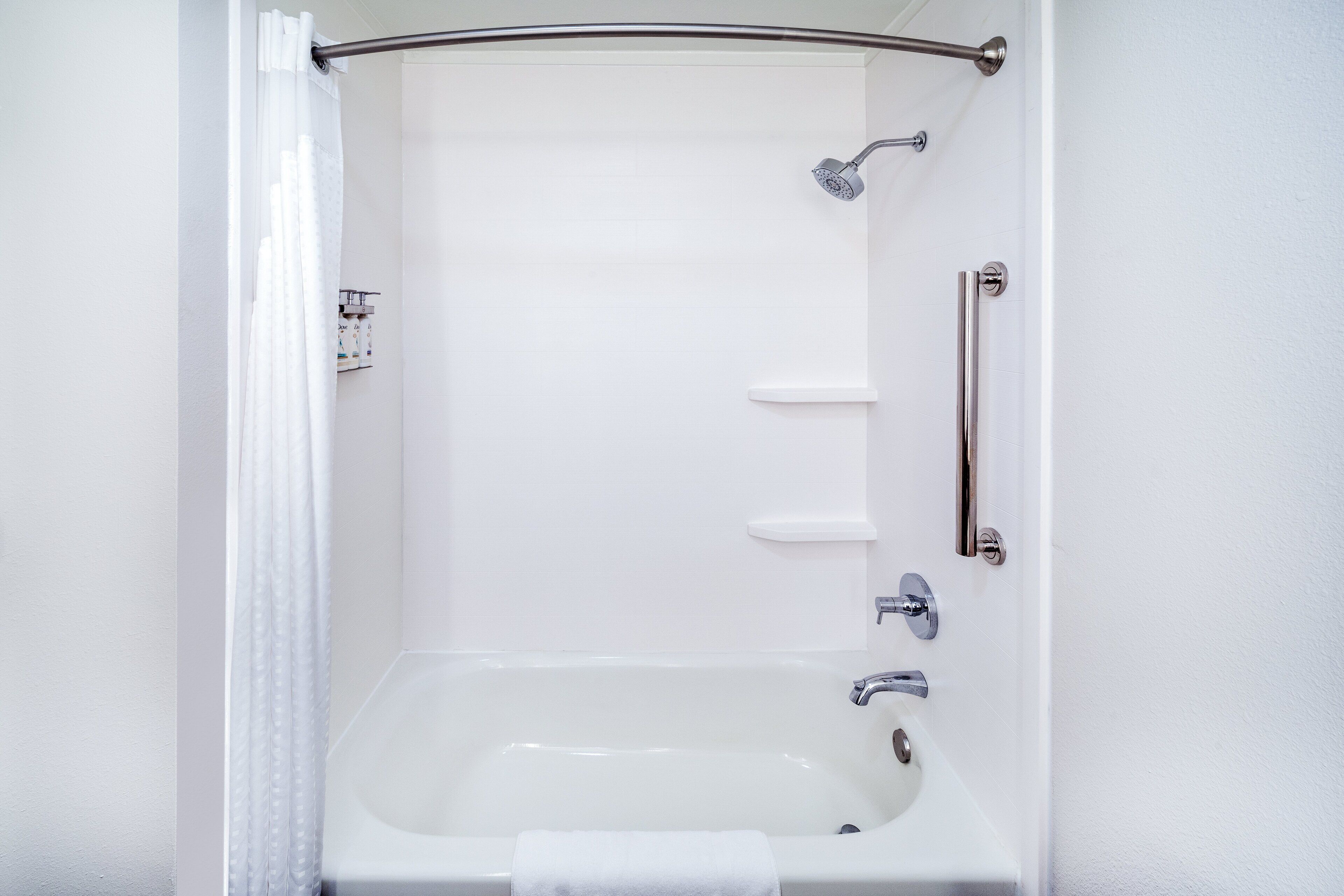 Un baño blanco con bañera, cabezal de ducha y baranda.