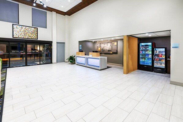 A spacious lobby with a reception desk, a vending machine, and a view of the kitchen area. - Holiday Inn Express & Suites Sulphur (Lake Charles) by IHG (Sulphur)