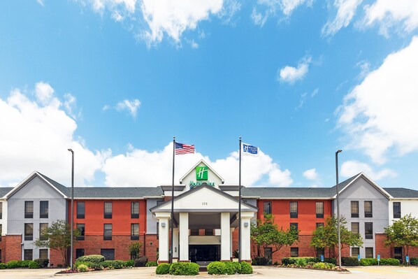 A hotel with a red and white facade, a central entrance, and American flags.