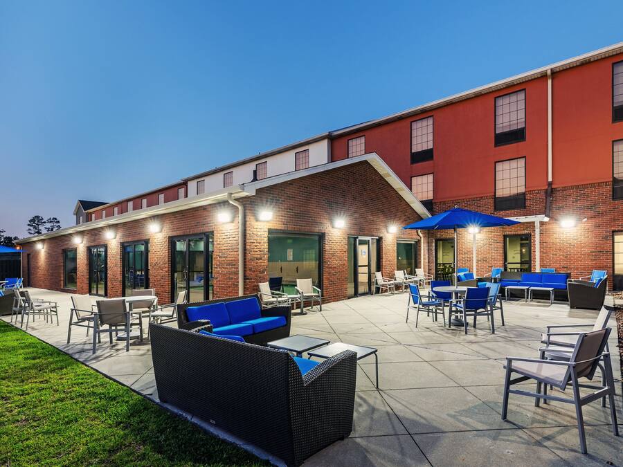 An outdoor patio area with seating and tables, a brick building, and a clear sky.