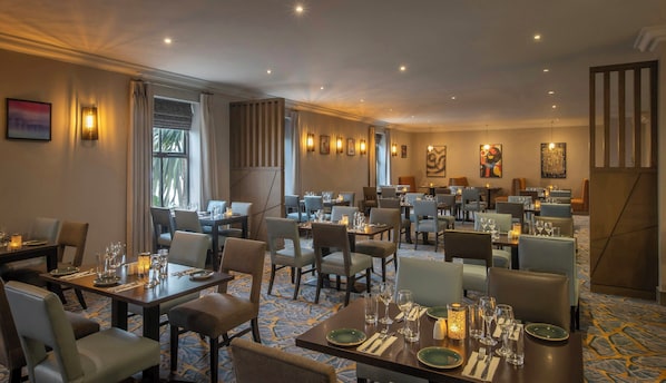 A restaurant with multiple tables, chairs, and ambient lighting.