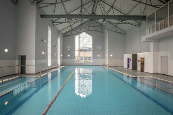 En inomhuspool med klart vatten, högt i tak och stora fönster.