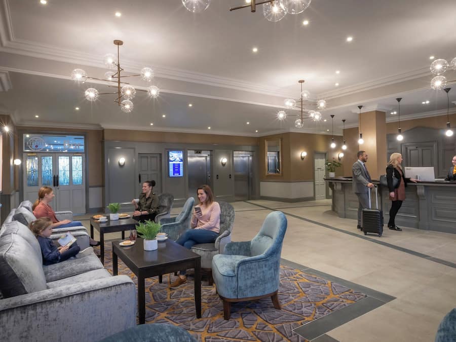 Un vestíbulo de hotel con zonas de estar, un mostrador de recepción y un bar.