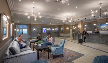 Un vestíbulo de hotel con zonas de estar, un mostrador de recepción y un bar.