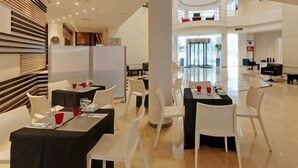 A modern hotel lobby with multiple dining tables, white chairs, and a spacious layout. - Hotel Ceuta Puerta de África (Ceuta)