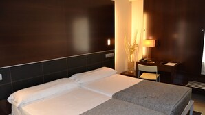 A hotel room with a large bed, a desk, a chair, and a lamp. - Hotel Ceuta Puerta de África (Ceuta)