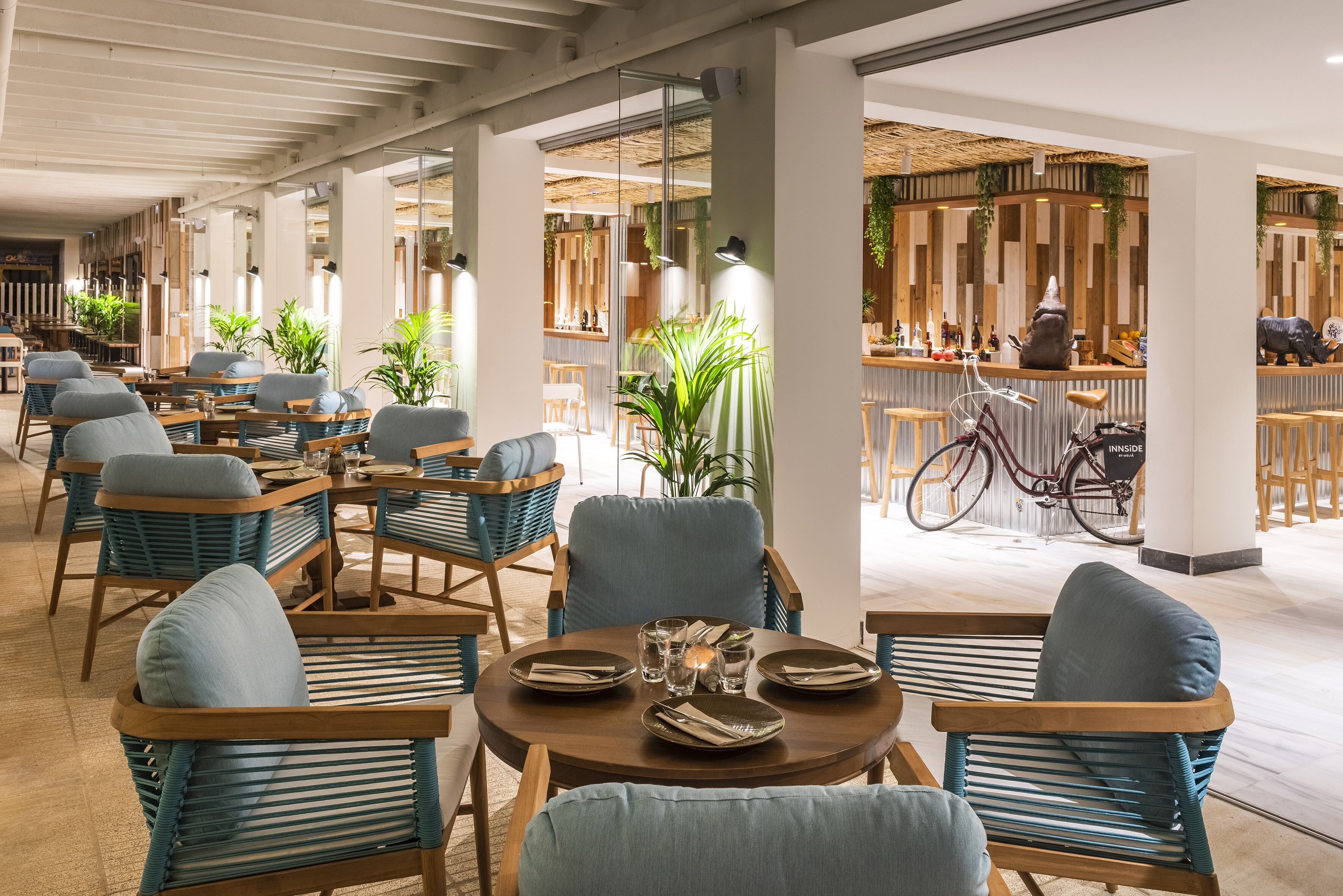 Un restaurante moderno con mesas redondas, sillas con acolchado azul y una bicicleta a la vista.