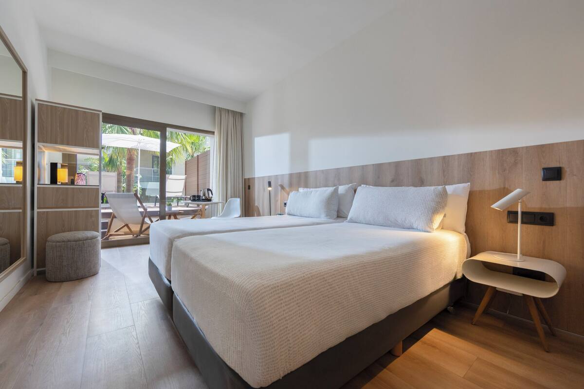 Une chambre d’hôtel moderne avec un grand lit, un petit coin salon et une vue sur l’extérieur.