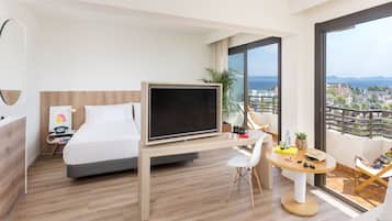 Una habitación de hotel moderna con cama, televisor, escritorio y balcón con vistas a la ciudad.
