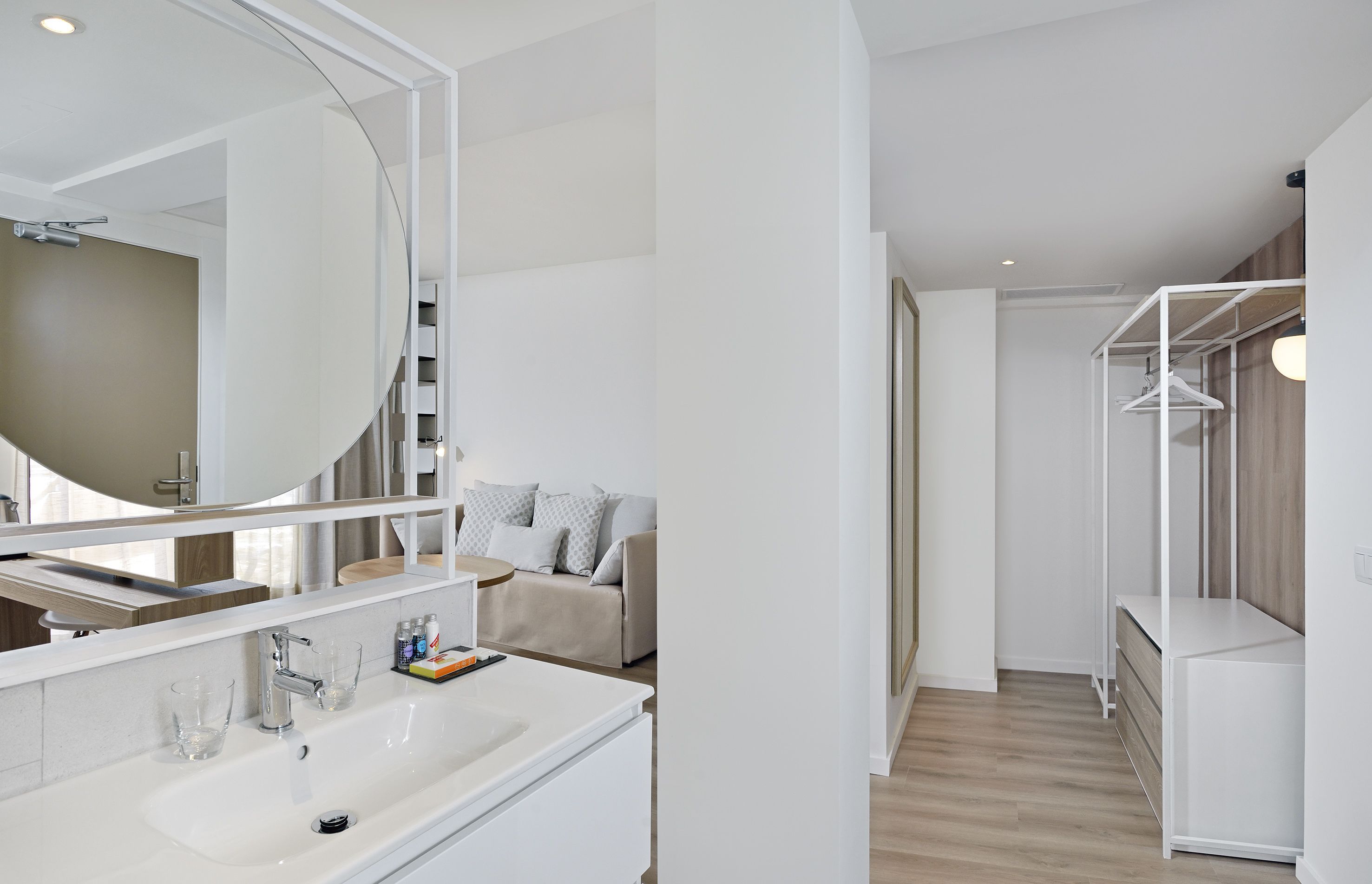 Une salle de bain moderne avec un grand miroir, un lavabo blanc et une douche à l’italienne.