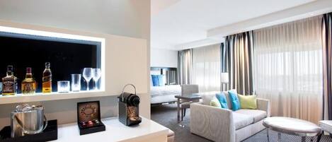 A hotel room with a bar area, a sofa, a small table, and a bed.