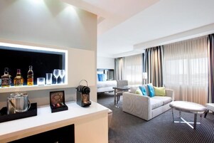 A hotel room with a bar area, a sofa, a small table, and a bed.